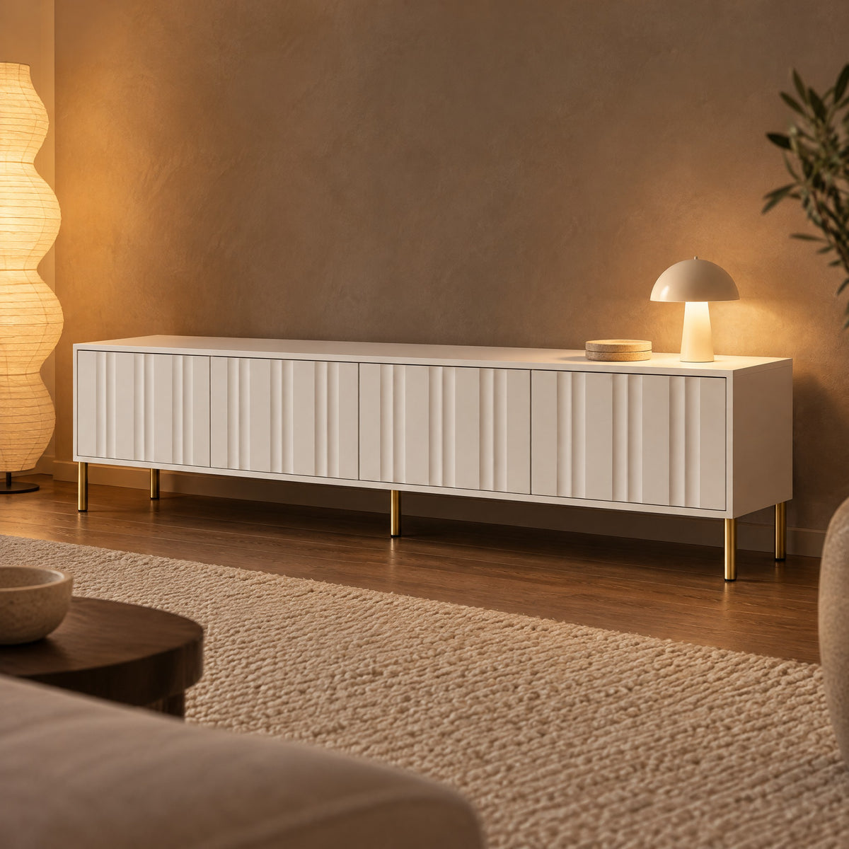 Meuble TV blanc façades ondulées pieds dorés 190 cm, dans un salon le soir